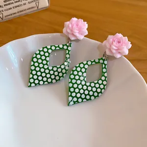 Close-up of vintage green polka dot leaf drop earrings with delicate pink resin roses