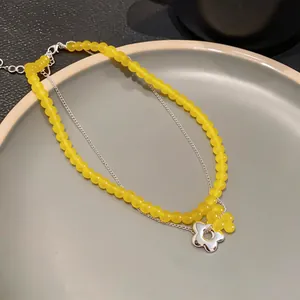 Detail of a French-style double-layer necklace with yellow beads and silver flower pendant.