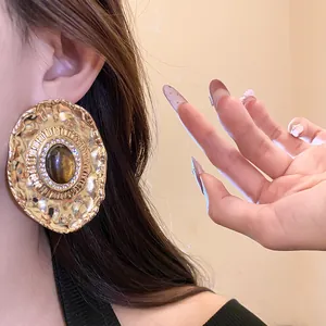Detail shot of vintage golden hammered earrings featuring a resin stone and rhinestone halo