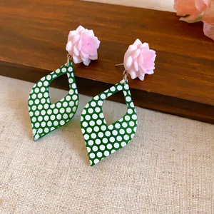 Close-up of vintage green and white polka dot flower earrings on wooden background