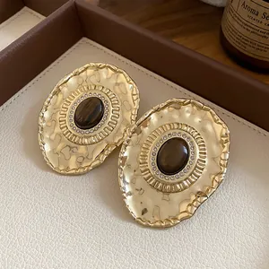 Detailed macro view of vintage palace style gold oval stud earrings with crystal halo