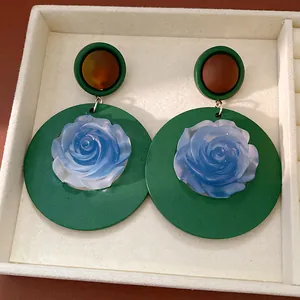 Close-up of vintage green resin earrings featuring intricate blue rose centerpieces.