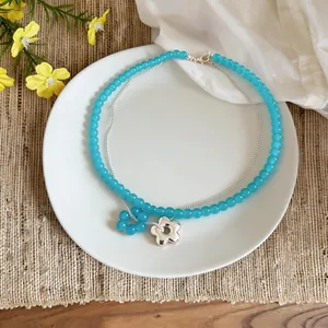 Detail view of a French-style double-layer necklace with blue glass beads and flower pendants.