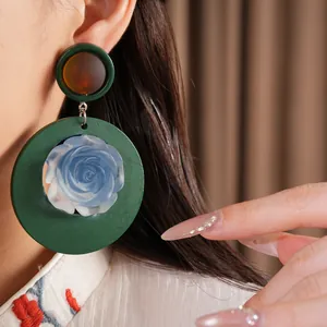 Detailed macro shot of vintage-style green resin earrings featuring a delicate blue rose