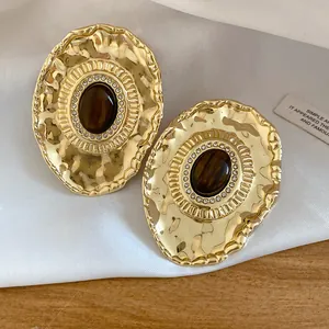 Close-up view of vintage gold-tone oval earrings with brown resin and rhinestones