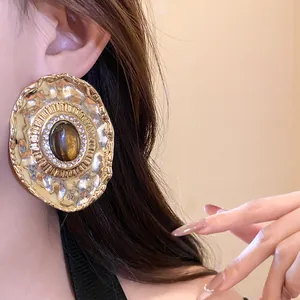 Detailed view of oversized vintage hammered gold earring with brown resin stone and crystals