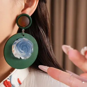 Close-up of vintage resin flower earrings with green round frame and blue rose