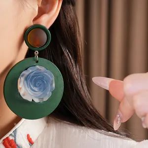 Detail view of resin blue rose earrings with green circular base in vintage style