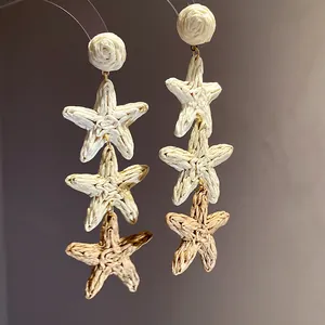 Gros plan de boucles d'oreilles étoiles de mer en raphia tressé de style bohème