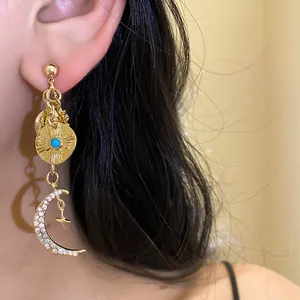Vue détaillée d'une boucle d'oreille dorée avec pendentifs lune et soleil étincelants