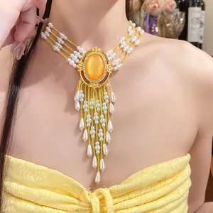 Detailansicht eines verzierten Perlen-Chokers mit orangefarbenem Edelstein und Quasten