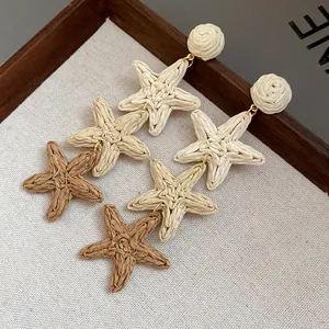 Gros plan détaillé des boucles d'oreilles pendantes étoiles de mer en raphia tressé