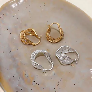 Detailed macro shot of elegant gold and silver twisted hollow earrings with zircon accents