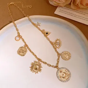 Gros plan d'un collier doré orné de breloques célestes vintage et de strass brillants.