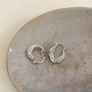 Close-up of twisted hollow geometric ear buckles with sparkling cubic zirconia stones