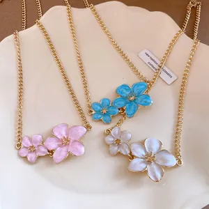 Detailed view of sweet style metal dripping oil flower necklaces in pink, blue, and white.