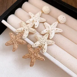 Détail de boucles d'oreilles en raphia tissé en forme d'étoile de mer dans un bel écrin