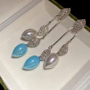Close-up of vintage leaf drop earrings with sparkling crystals and teardrop beads.