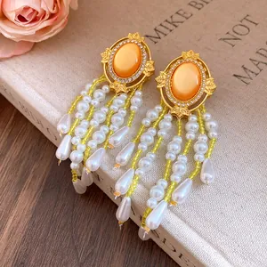 Detailansicht luxuriöser Tropfenohrringe mit orangefarbenen Cabochons und Perlen