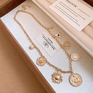 Vue détaillée de breloques dorées vintage avec motifs œil, soleil et lune sur collier