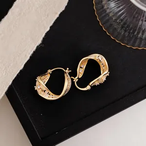 Detailed view of gold twisted hollow hoop earrings with shimmering cubic zirconia accents.