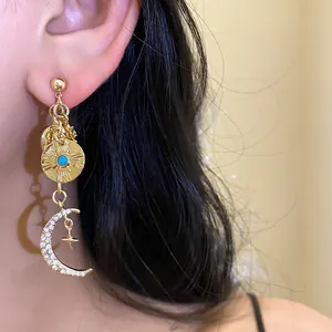 Vue détaillée de boucles d'oreilles dorées avec breloques lune, soleil et strass étincelants