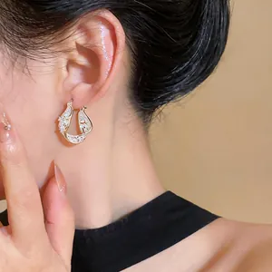 Detailed close-up of elegant gold twisted hollow hoop earrings with zircon pavé being worn