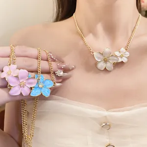 Close-up detail view of retro metal dripping oil flower necklaces on model neck and hand