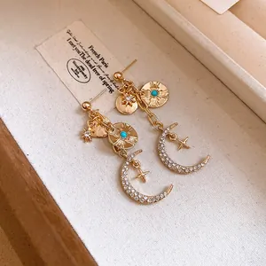 Détail de boucles d'oreilles pendantes lune et étoile dorées à strass de style français