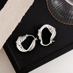 Macro view of elegant silver twisted geometric hoop earrings with sparkling zircon inlays.