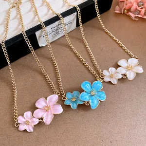 Detailed macro view of gold flower enamel necklaces in pink, blue, and white tones