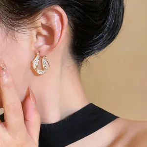 Detail of elegant gold twisted hollow geometric hoop earring with zircon inlay