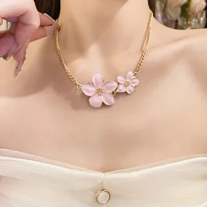 A detailed close-up shot of a sweet pink enamel flower necklace with gold chain.