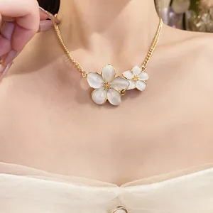 Detailed view of elegant gold-toned chain necklace with white enameled flower pendants