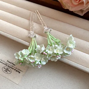 Detailed close-up of elegant white and green floral hair forks for spring hair styling.
