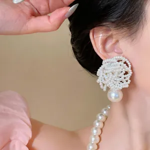 Detailed macro view of elegant beaded flower pearl drop earring worn by a model