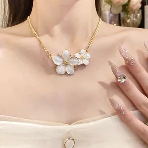 Close-up detail of a vintage style white enamel flower necklace worn on a gold chain