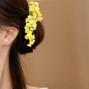 Detailed macro view of yellow floral hair pin on brunette hair with soft spring style