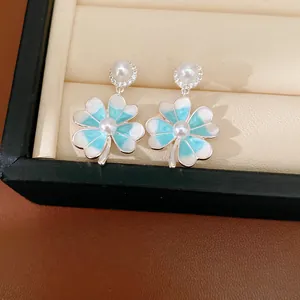 Detailed macro view of elegant blue enamel clover flower earrings with pearls and zircons