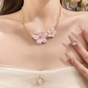 Close-up of pink enamel flower necklace on model's neckline for sweet vintage look