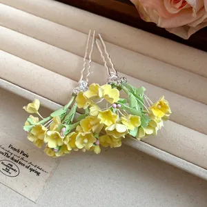 Detailed close-up of handmade yellow flower hairpins displayed on a beige jewelry tray.