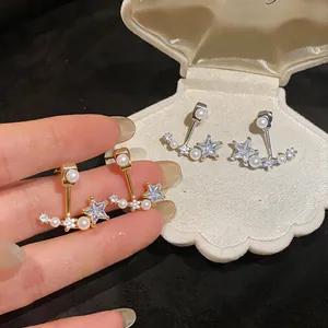 Close-up detail of star-shaped zircon and pearl stud earrings in gold and silver finishes