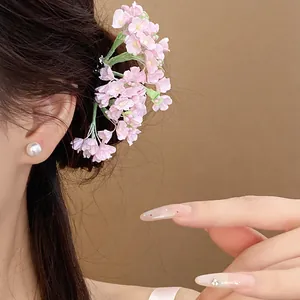 Close-up view of a delicate pink floral hairpin on a woman with elegant pearl earring