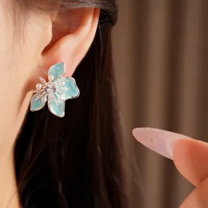 Detailed view of elegant blue enamel flower stud earrings with zircons and pearls on ear.