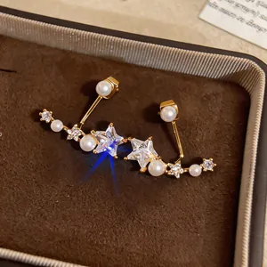 Macro shot of gold-plated star earrings with cubic zirconia and pearls in a brown box