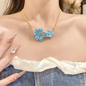 Close-up of elegant gold chain necklace with dual blue enamel flower pendants