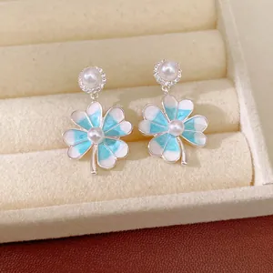 Close-up of blue and white enamel four-leaf clover earrings with pearls and zircons