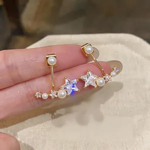 Detailed macro view of elegant star-shaped zircon and pearl earrings with gold finish
