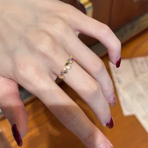 Detailed close-up shot of a delicate golden leaf ring with vibrant colorful zircon stones
