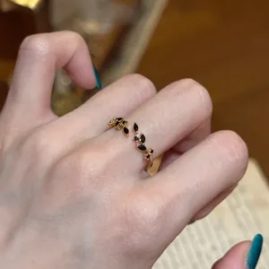 Close-up of a vintage-style open ring featuring black zircon leaves on an index finger.